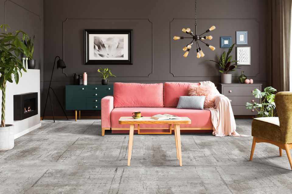 gray patterned carpet in jewel toned living room with pink velvet couch and accent lighting